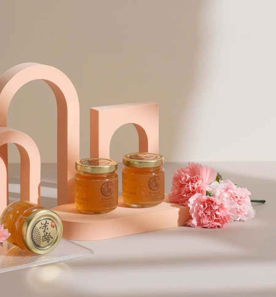 Golden jars of Froscale collagen jelly among peach arches and carnations